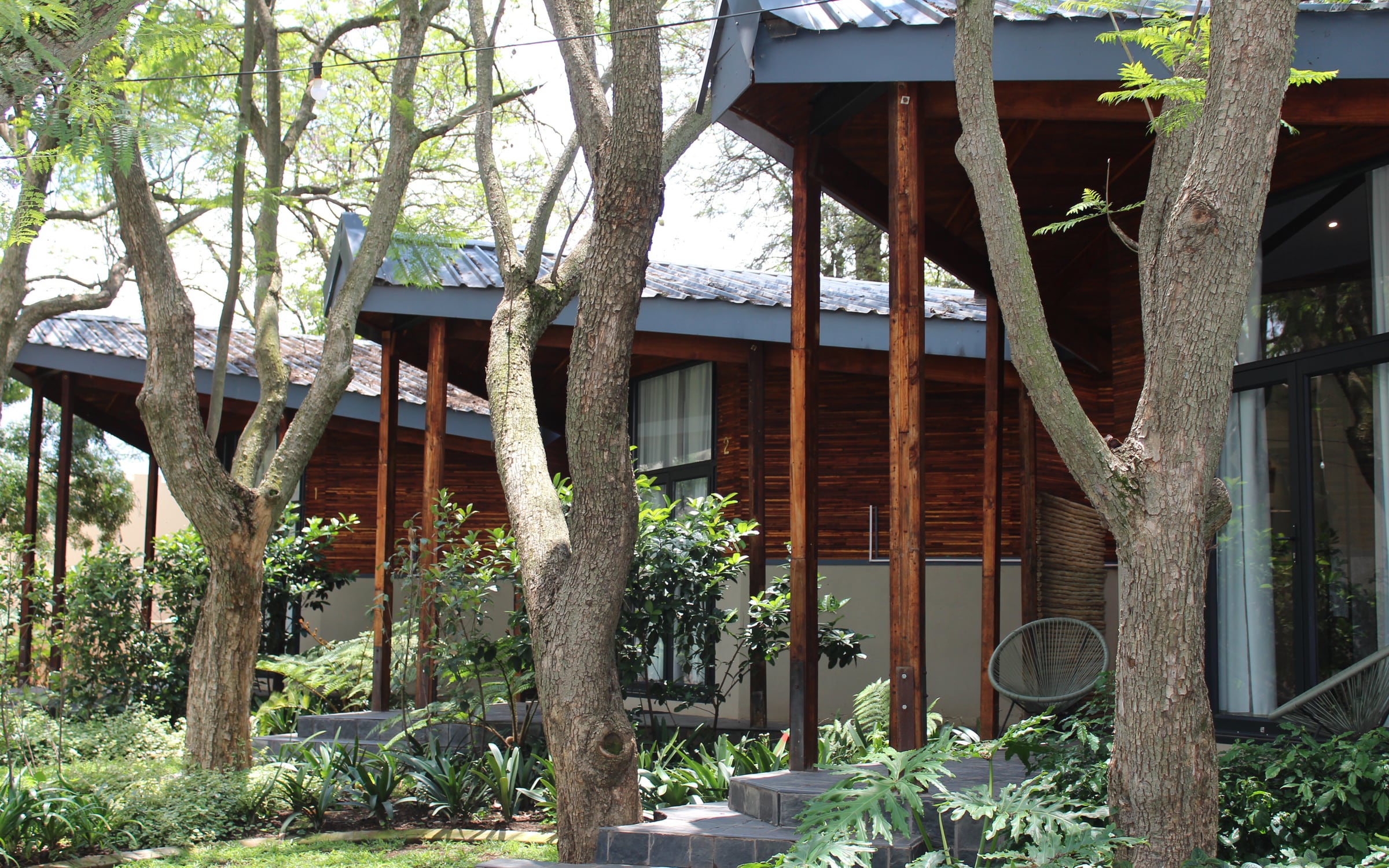 Timber-clad glamping units set among mature trees at Qurtuba.